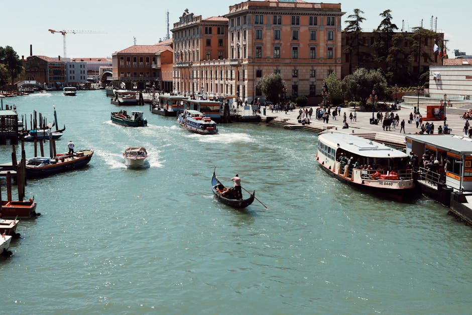 Lively scene of the Grand Canal in Venice, Italy, showcasing gondolas and boats against historic architecture.