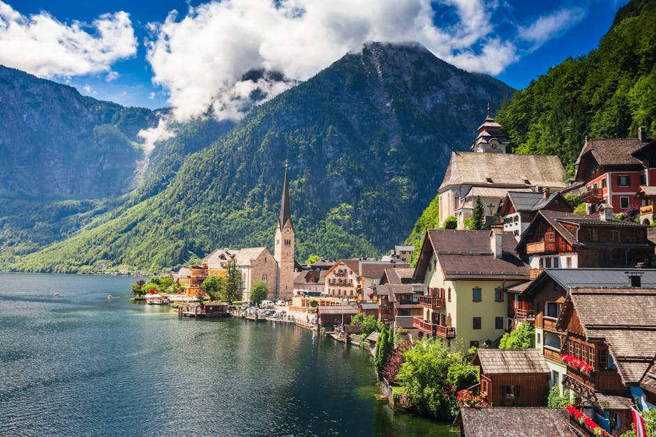 Picturesque view of Hallstatt's lakeside with mountains, summer greenery.