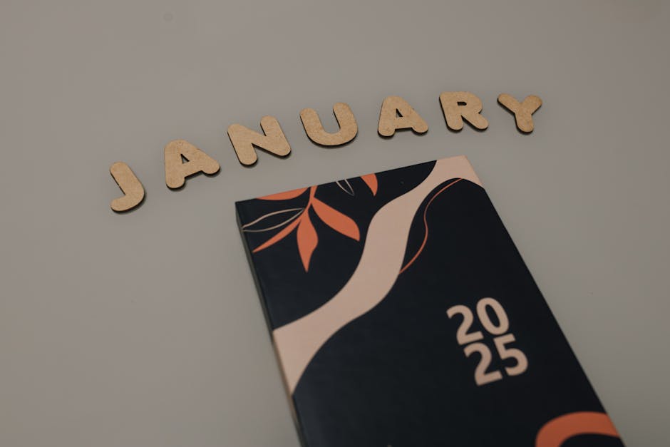 Flat lay of a 2025 planner with 'January' spelled in wooden letters. Perfect for organization lovers.