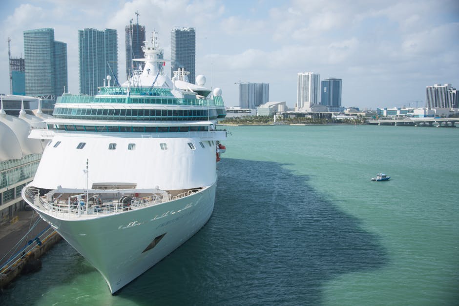Cruise ship docked in Miami with skyscrapers in the background under a clear sky.