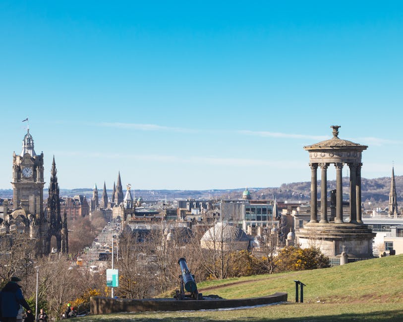 A panoramic view from Calton Hill highlighting Edinburgh's historic architecture under a bright sky.